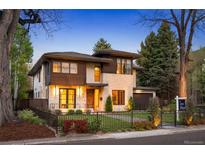 Beautifully landscaped two-story home featuring stone and wood facade, manicured lawn, and black metal fencing at 424 Grape St, Denver, CO 80220