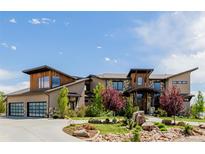 Stunning custom home with stone accents, modern design, lush landscaping, and a three-car garage at 2466 Spruce Meadows Dr, Broomfield, CO 80023