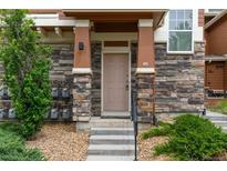 Charming front door with stone accents, concrete steps, and a well-maintained landscape at 7130 Simms St # 206, Arvada, CO 80004