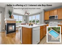 Bright kitchen featuring an island with a white countertop, wood cabinets, and a cozy fireplace at 7130 Simms St # 206, Arvada, CO 80004