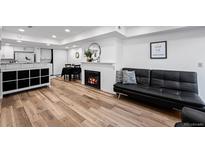 Inviting living room features a cozy fireplace, modern black couch and an open floor plan with hardwood flooring at 8701 Huron St # 1-212, Thornton, CO 80260