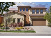 Charming two-story home featuring a stone facade and a well-manicured front yard with colorful landscaping at 15179 W Washburn Ave, Lakewood, CO 80228