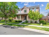 Charming two-story home featuring a covered front porch, lush landscaping, and inviting curb appeal at 11093 Nome St, Commerce City, CO 80640