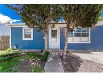 Charming blue home with a well-manicured front yard and white door, framed by mature trees at 770 Havana St, Aurora, CO 80010