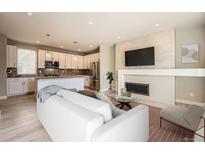Open-concept living room features a fireplace, a mounted TV, and seamless flow into the kitchen at 701 E 24Th Ave, Denver, CO 80205