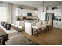 Bright eat-in kitchen features white cabinets, stainless steel appliances, and an island with bar stool seating at 4090 Estrella St, Brighton, CO 80601