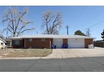 Cozy brick ranch-style home with an attached two-car garage, set on a lot with mature trees at 306 Empire St, Aurora, CO 80010