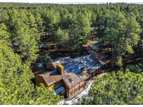 Stunning aerial view of home nestled in a serene forest setting, surrounded by lush greenery and mature trees at 18680 Arrowwood Dr, Monument, CO 80132