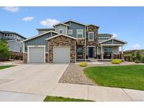 Beautiful two-story home with a stone and blue siding exterior and a well-manicured lawn at 21854 Tyrolite Ave, Parker, CO 80138