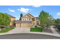 Two-story home with tan exterior, large windows, three car garage, and manicured front lawn at 22302 Quail Run Way, Parker, CO 80138