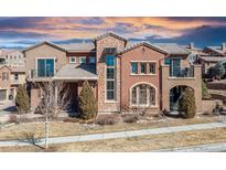 Stunning multi-story home showcases a mix of stone and stucco, complemented by a tile roof and a colorful sunset at 9340 Sori Ln, Highlands Ranch, CO 80126
