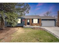 Charming one-story home with a well-maintained lawn, brick accents, and a welcoming front porch with seating at 8606 W Geddes Pl, Littleton, CO 80128