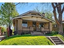 Charming brick home featuring a covered porch, manicured lawn, and easy access via concrete steps at 810 Adams St, Denver, CO 80206