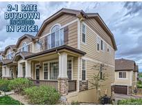 Inviting tan-colored townhouse featuring a cozy front porch with stone accents and well-maintained landscaping at 1436 Turnberry Dr, Castle Rock, CO 80104