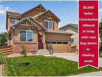 Charming two-story home featuring a well-maintained lawn, brick accents, and an attached two-car garage at 17035 E 102Nd Pl, Commerce City, CO 80022