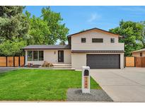 Charming two-story home with a well-manicured lawn and modern architectural details and a gray garage door at 7684 S Ingalls St, Littleton, CO 80128