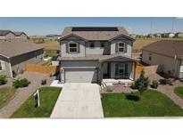 Charming two-story home with a well-maintained front yard, two-car garage, and solar panels on the roof at 7414 Blue River Ave, Frederick, CO 80530
