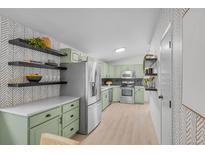 Bright kitchen features stainless steel appliances, sleek countertops, modern backsplash, and decorative floating shelves at 3619 N York St, Denver, CO 80205