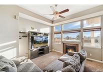 Comfortable living room with a cozy fireplace and large windows at 9752 Dahlia Ln, Thornton, CO 80229