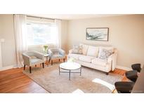 Bright living room with hardwood floors, neutral tones, and a comfortable seating arrangement, creating a welcoming atmosphere at 7100 Saulsbury St, Arvada, CO 80003