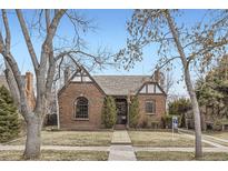 Charming brick home with Tudor accents, arched window, and inviting front yard at 2080 Leyden St, Denver, CO 80207