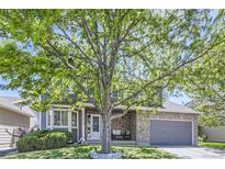 Charming two-story home with a stone facade and well-maintained front yard and large tree providing shade at 11218 Newark Ct, Commerce City, CO 80640