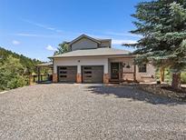 Beautiful exterior features a gray home with two-car garage, front porch and lots of parking space at 31518 Niakwa Rd, Evergreen, CO 80439