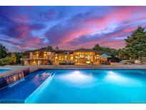 Stunning pool with integrated waterfall feature, deck area, and beautiful views of the estate at sunset at 5727 Colorow Dr, Morrison, CO 80465