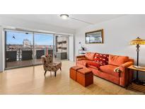 Bright living room with city view, featuring orange couch and comfy chair at 800 N Washington St # 710, Denver, CO 80203