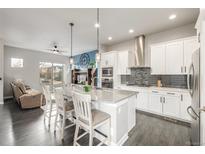 Bright, open kitchen featuring a center island with bar seating, stainless appliances, and wood floors at 6777 Larsh Dr, Denver, CO 80221