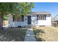 Charming single-story home with gray siding, black door, and tidy front yard landscaping under a clear blue sky at 7111 Clermont St, Commerce City, CO 80022