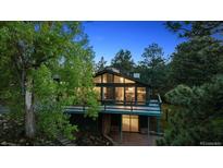 Charming home with a spacious deck and large windows, surrounded by lush greenery and trees at 21859 Grandview Ave, Golden, CO 80401