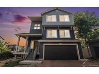 Two-story home featuring a black garage door, blue siding and covered front porch at 20031 Elgin Dr, Denver, CO 80249