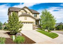 Stunning two-story home featuring a two-car garage and manicured front yard with mature trees under a bright blue sky at 2115 Holmby Ct, Castle Rock, CO 80104