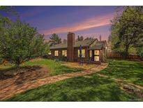Beautiful brick home featuring a spacious backyard with a brick patio and lush green lawn under a colorful sunset at 1900 Magnolia St, Denver, CO 80220