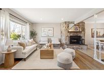 Inviting living room with stone fireplace, hardwood floors, and modern furnishings at 6371 Iris Ct, Arvada, CO 80004