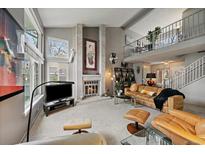 Spacious living room with fireplace, plush seating, and abundant natural light from the large windows at 1571 S Trenton Ct, Denver, CO 80231