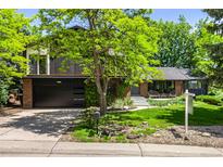 Charming two-story home with a lush front yard, mature trees, and a brick facade at 7234 S Kendall Ct, Littleton, CO 80128