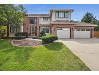 Attractive two-story home featuring a manicured lawn and a three-car garage, blending brick and stucco at 16326 E Dorado Ave, Centennial, CO 80015