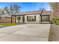 Charming painted brick home featuring a large driveway, covered porch, and manicured landscaping at 2441 Niagara St, Denver, CO 80207
