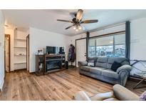 Inviting living room features wood floors, a ceiling fan, fireplace, and a large window for natural light at 7940 Pontiac St, Commerce City, CO 80022
