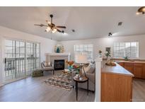 Bright living room features a fireplace, ceiling fan, sliding glass door to balcony, and sleek gray laminate flooring at 3260 E 103Rd Pl # 912, Thornton, CO 80229