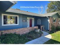 Charming single-story home with a well-manicured lawn, a red door, and a brick wall at 835 Noble Ct, Golden, CO 80401