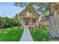 Charming two-story home boasts a well-maintained lawn and inviting front porch with wood columns at 2870 N Raleigh St, Denver, CO 80212