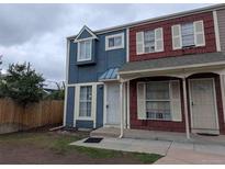 Two-story townhouse featuring blue and red siding, white trim, and a small front lawn at 15703 E 13Th Pl, Aurora, CO 80011