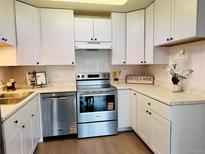 Charming kitchen featuring white cabinetry, stainless steel appliances, and stylish countertops at 755 S Alton Way # 12C, Denver, CO 80247