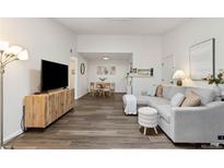 Bright living room with gray sectional, wood-look floors, and open dining area at 18391 E Kepner Pl # 205, Aurora, CO 80017