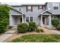 Charming townhome featuring a covered porch, landscaped front yard, and red door at 19249 E 58Th Ave # D, Denver, CO 80249