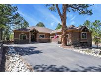 A single Gathering house with stone and stucco accents, long paved driveway, and manicured landscaping at 670 Independence Dr, Larkspur, CO 80118