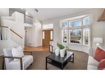 Bright living room with a bay window, hardwood floors, and a staircase leading to the second floor at 8825 Fairview Oaks Pl, Lone Tree, CO 80124